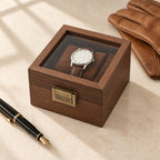 Walnut-finish single watch box closed, beside a fountain pen and leather gloves