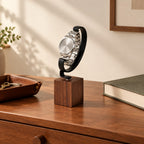 Walnut watch hook stand on a chest of drawers beside a valet tray and a book