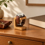 Wooden single watch stand on a chest of drawers beside a valet tray and a book
