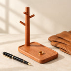 Wooden valet tray with a watch and key stand, beside a fountain pen and leather gloves