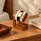 Wooden watch pillow stand on a nightstand beside a valet tray and a book